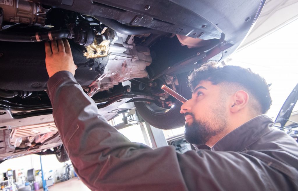 An auto mechanic works on a vehicle after a likely diagnosis using a code reader for your car.
