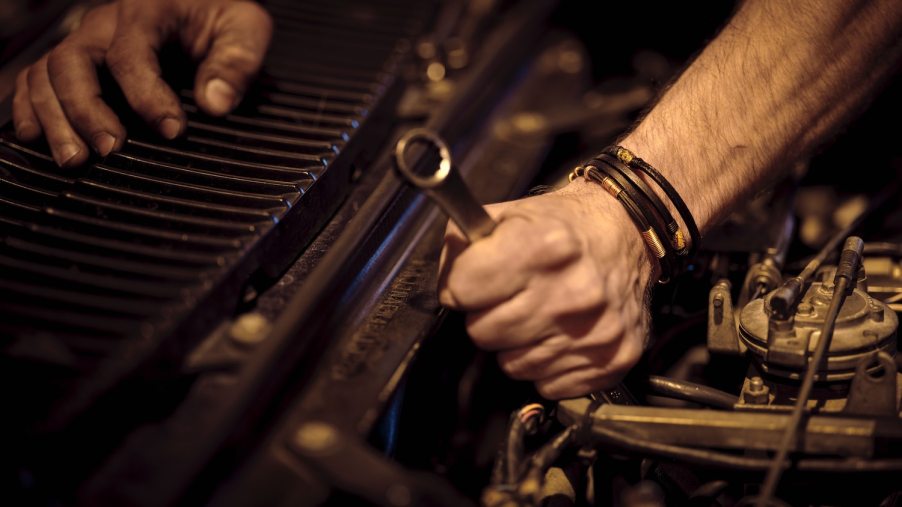 Closeup of a mechanic working on an old car.