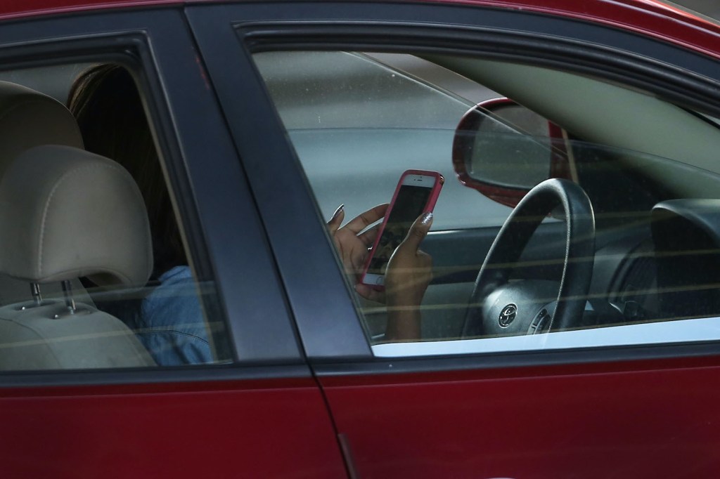 A driver plays on their phone while driving.