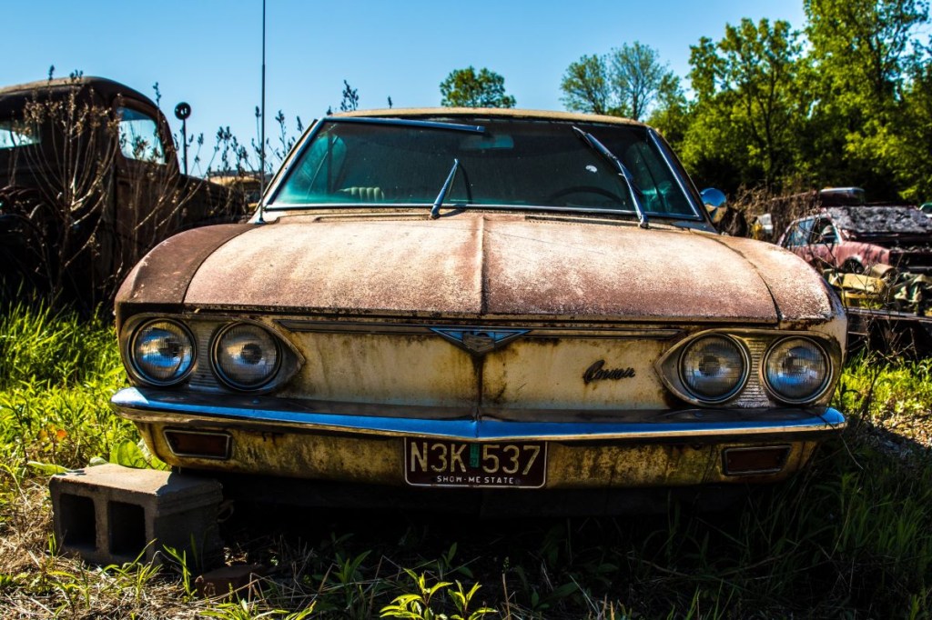 Junkyard parts surrounding a rusted old car in a scrapyard