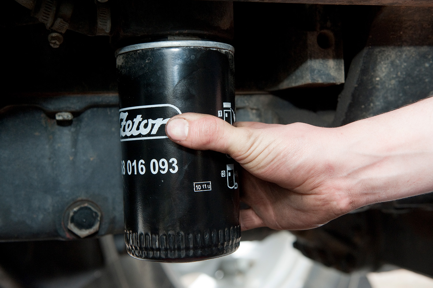 Hand isntalling an oil filter on a tractor engine