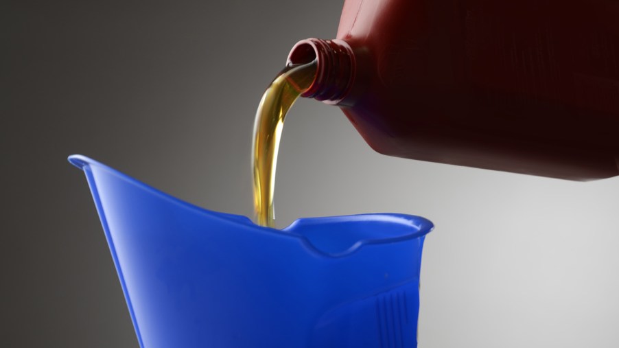 Close-up view of motor oil as it is poured from a red container into a blue bucket