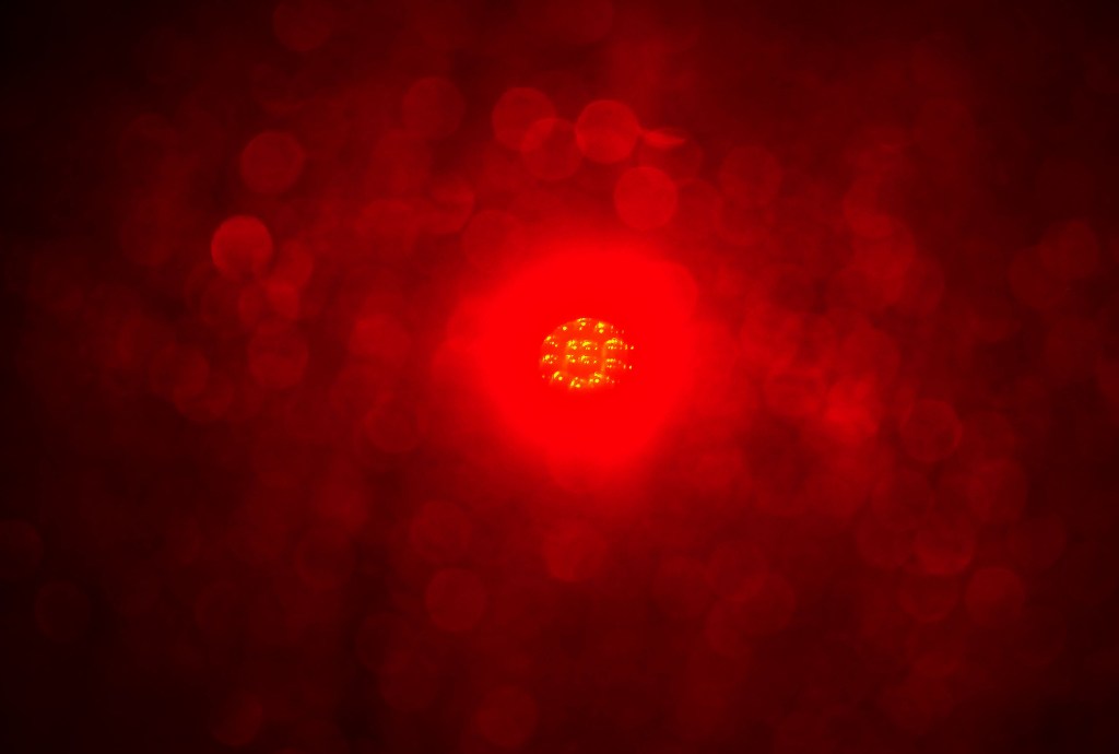 An obscured red light seen through a foggy windshield