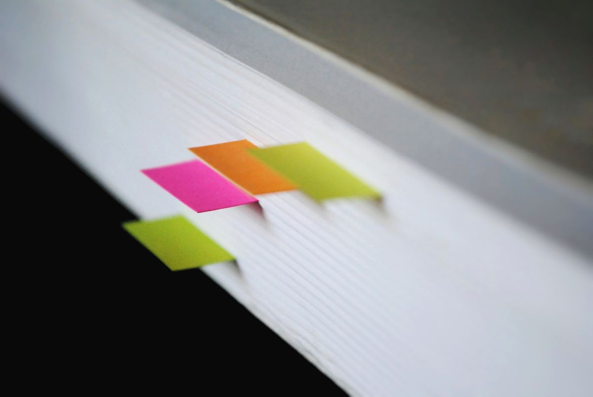 Close up of a book of papers with small, colorful bookmarks poking out