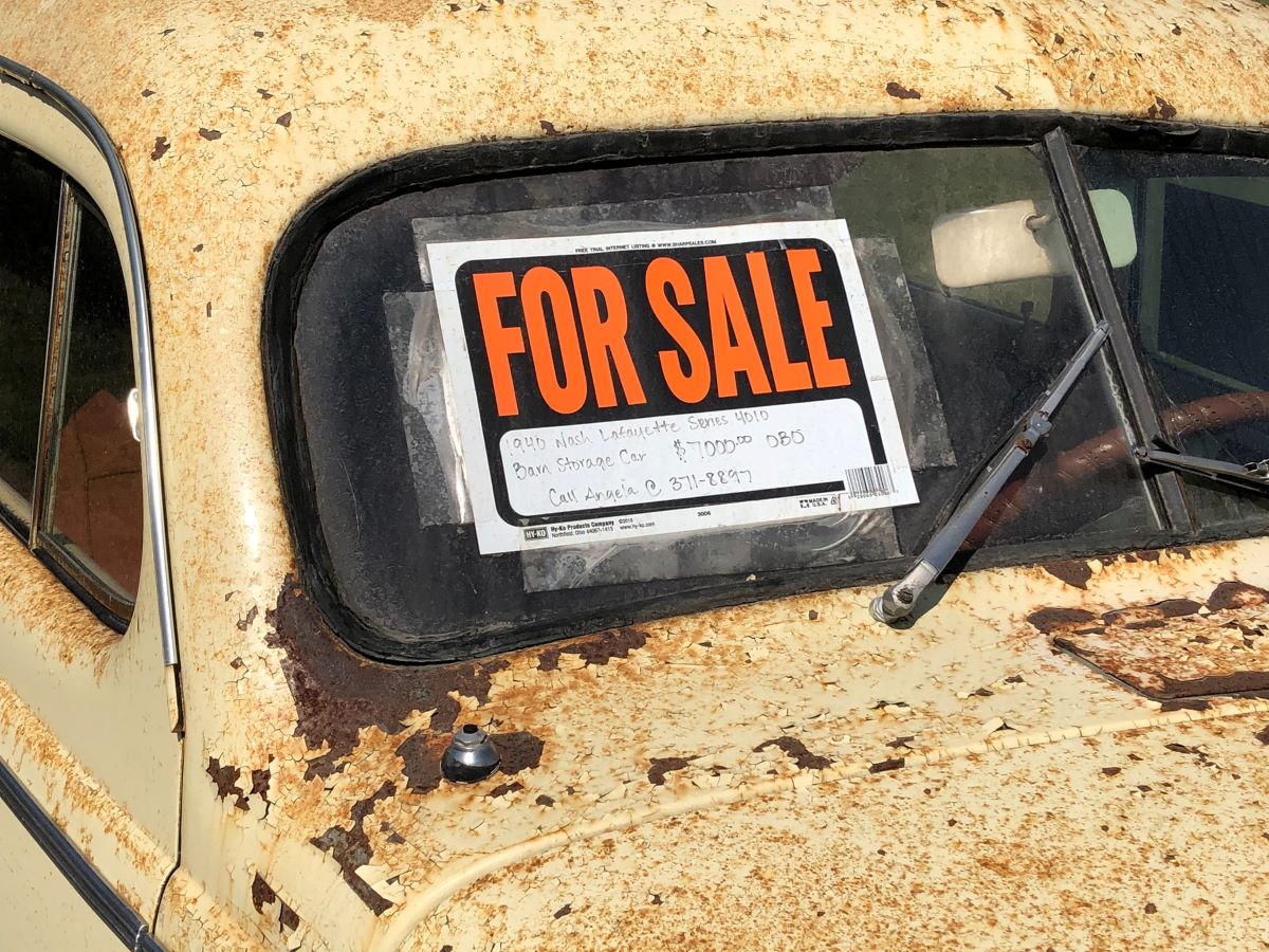 A For Sale sign on a rusted old classic car advertises a shed storage truck;  this car is not going to the scrap heap