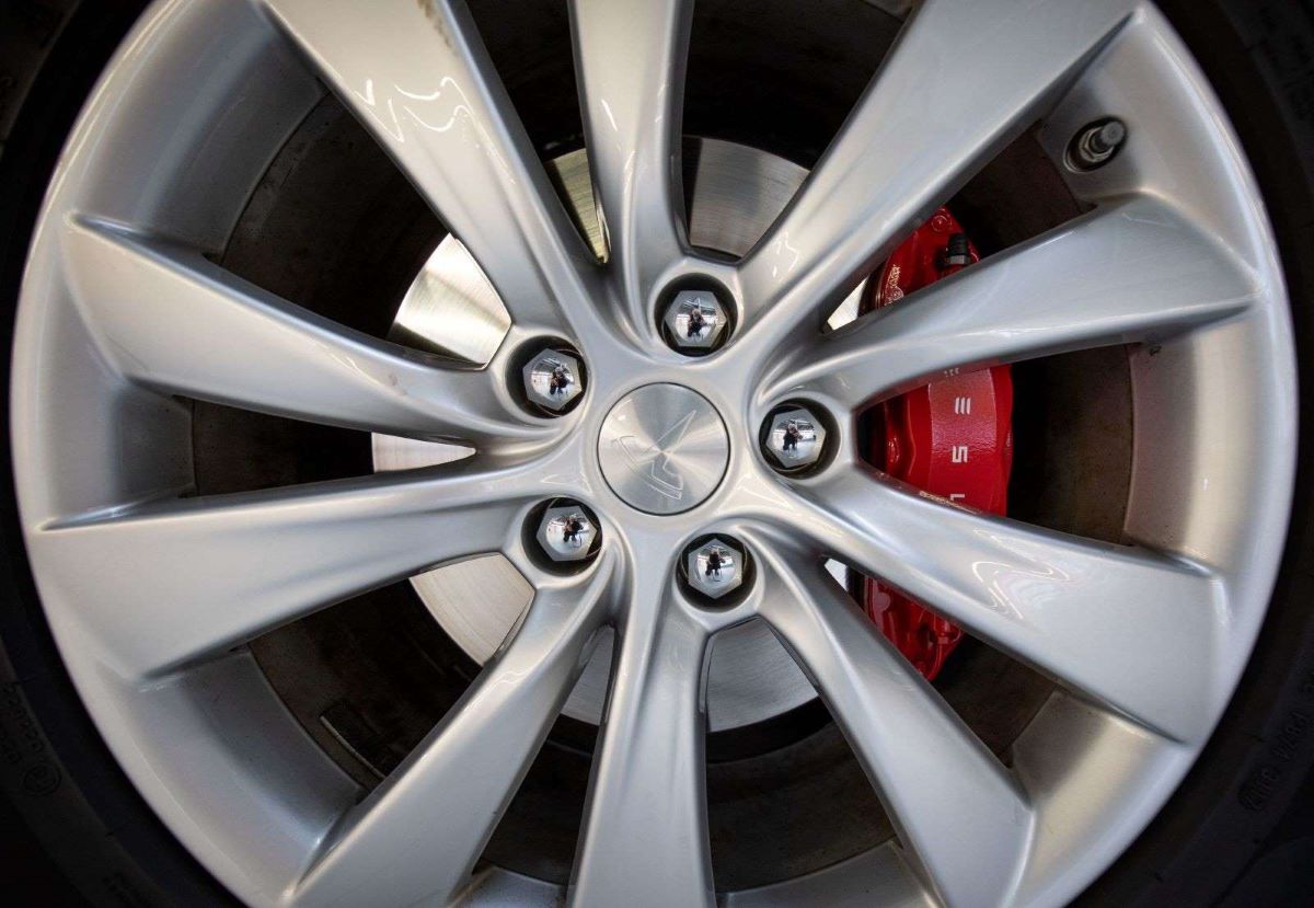 Close-up shot of a Tesla wheel, showing a red EV brake caliper