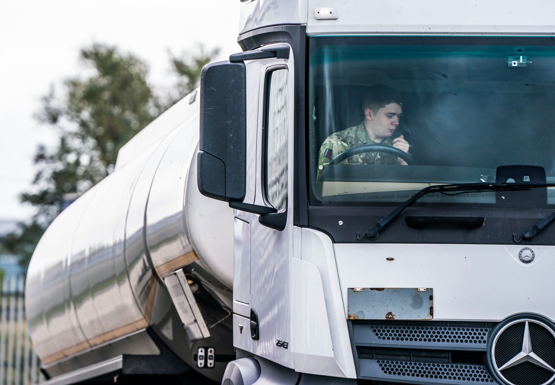 A truck driver in a military uniform driving a Mercedes-Benz lorry tanker near Goole, Yorkshire