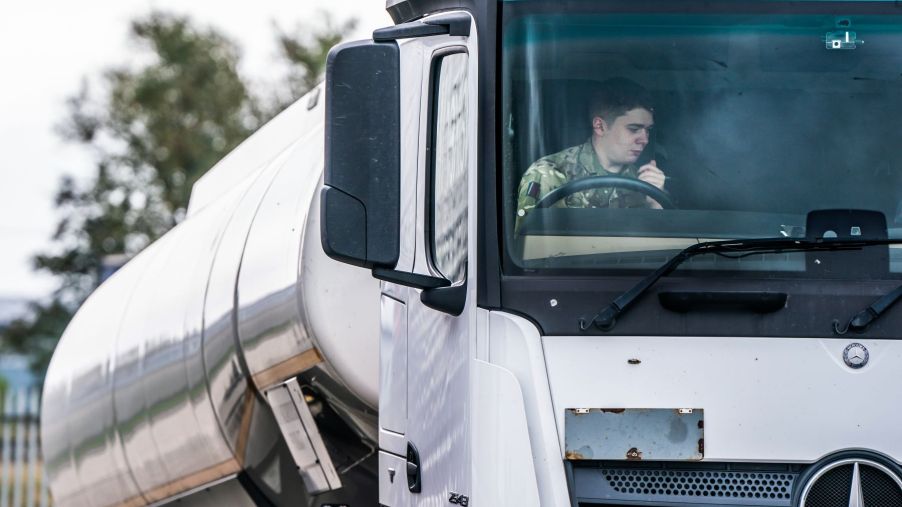 A truck driver in a military uniform driving a Mercedes-Benz lorry tanker near Goole, Yorkshire