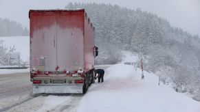 A trucker adding snow chains to tires during a winter drive in Bavaria, Wildpoldsried