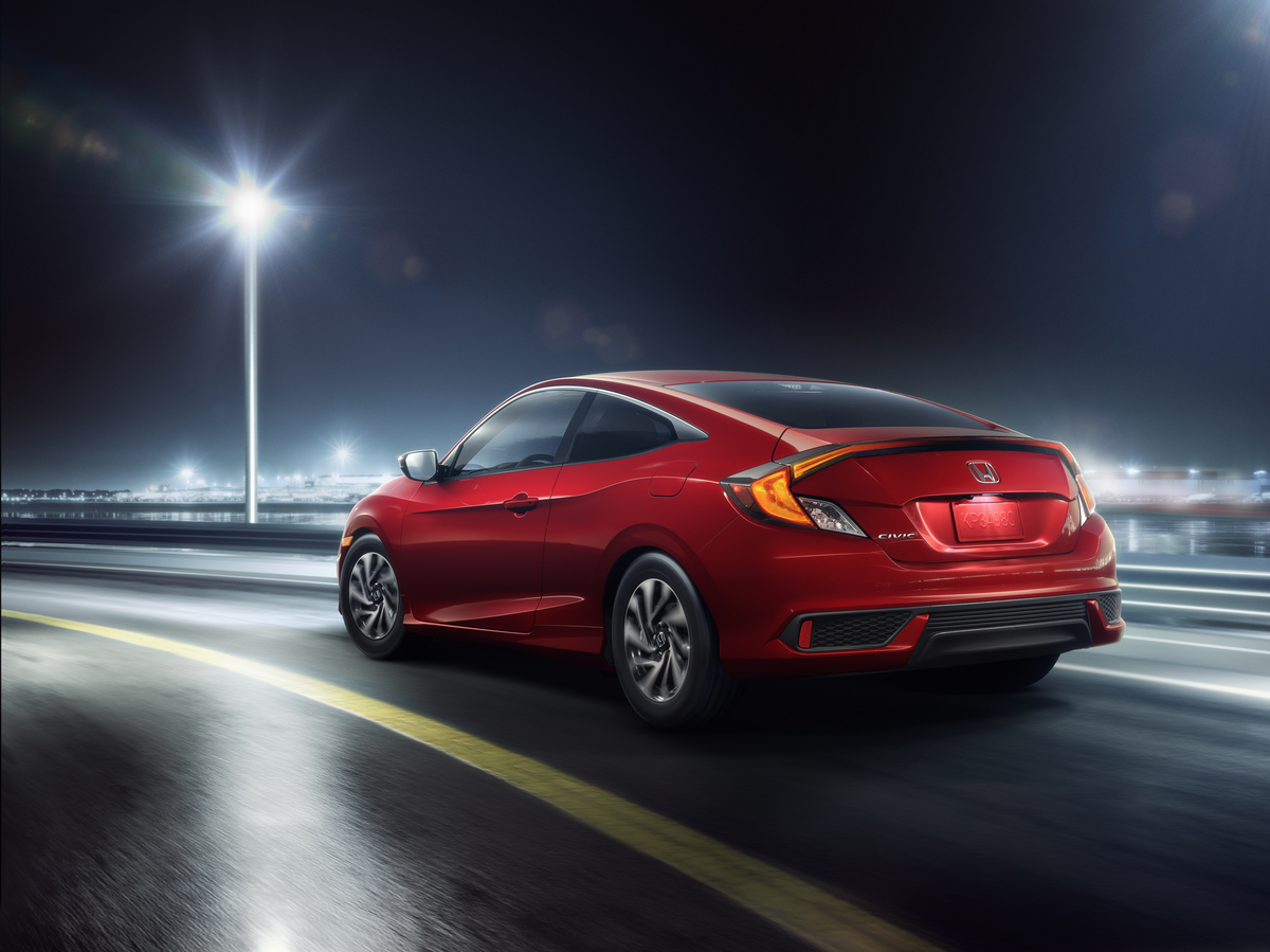 Used red 2020 Honda Civic Coupe driving at night on the highway with street lamps