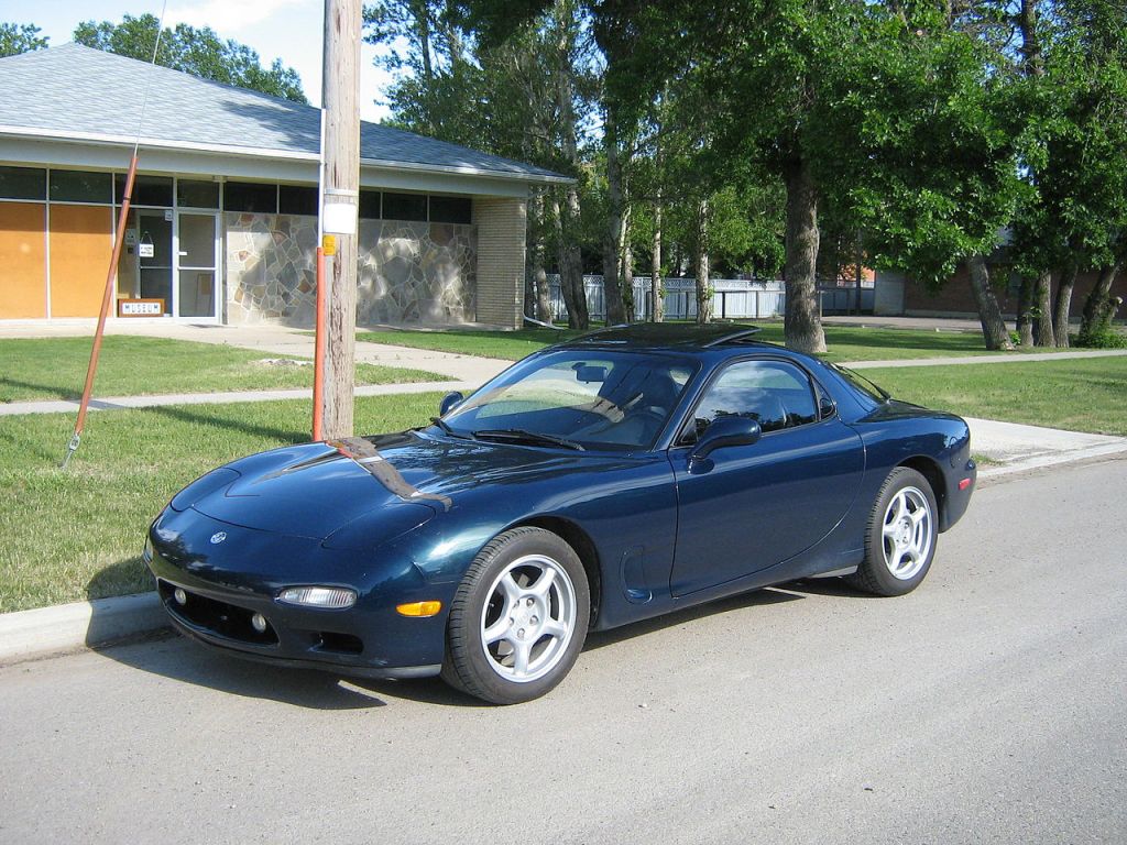 A blue 1993 Mazda RX-7 parked on the side of the street