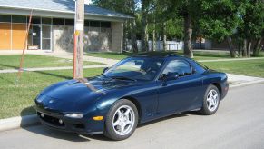 A blue 1993 Mazda RX-7 parked on the side of the street
