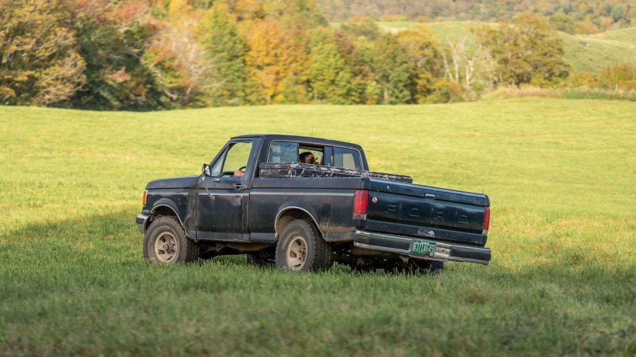 Black pickup truck driving through a field.