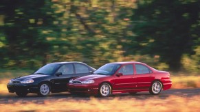 A red and a black 2000 Ford Contour SVT drive down a country road