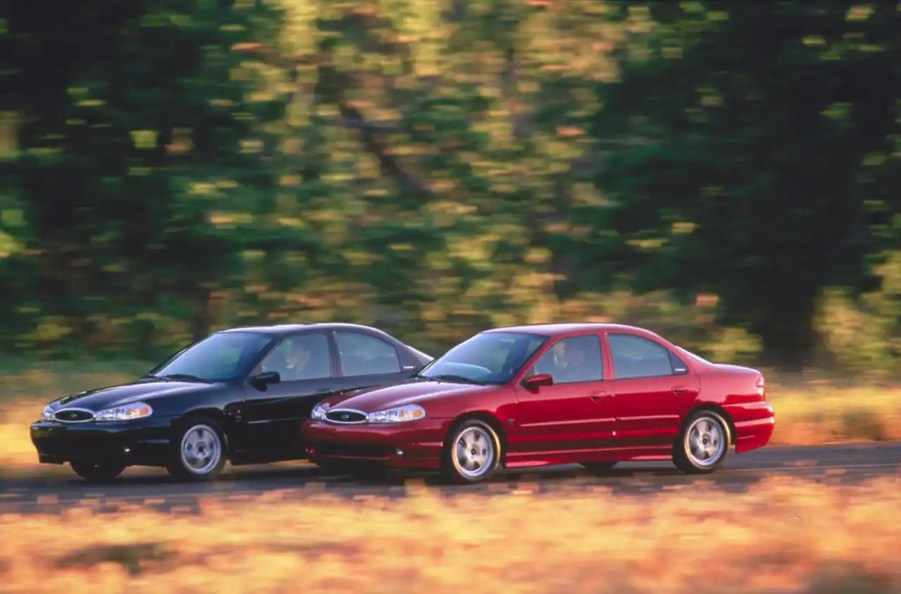A red and a black 2000 Ford Contour SVT drive down a country road