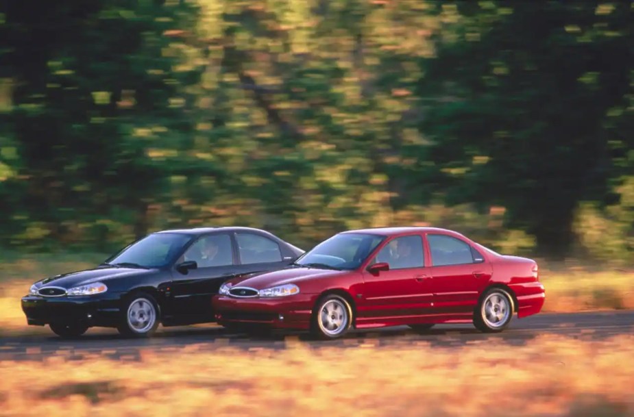 A red and a black 2000 Ford Contour SVT drive down a country road