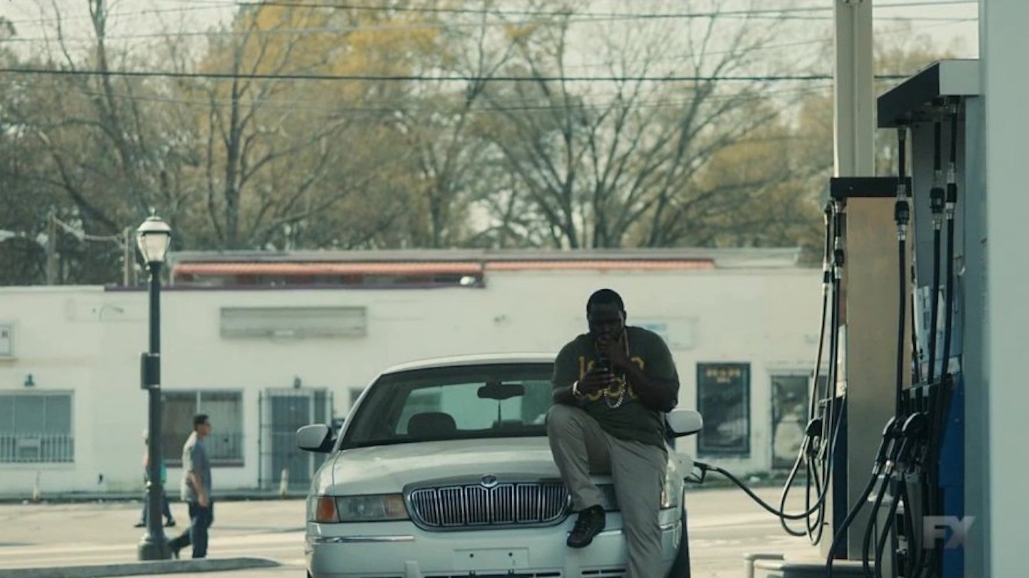 Brian Tyree Henry's Paper Boi sits on the hood of his 2000 Mercury Grand Marquis during Donal Glover's Atlanta TV show.