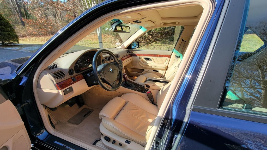 The tan-leather front seats and wood-trimmed tan dashboard of a blue 2001 E38 BMW 740i M Sport