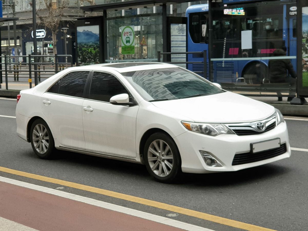 A white 2011 Toyota Camry, one of the most reliable cars, parked on a street in the city