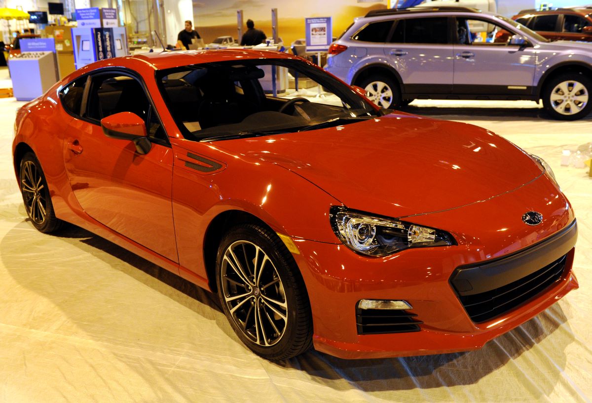 Red 2013 Subaru BRZ at an auto show; the BRZ history started with this model year
