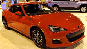 Red 2013 Subaru BRZ at an auto show; the BRZ history started with this model year
