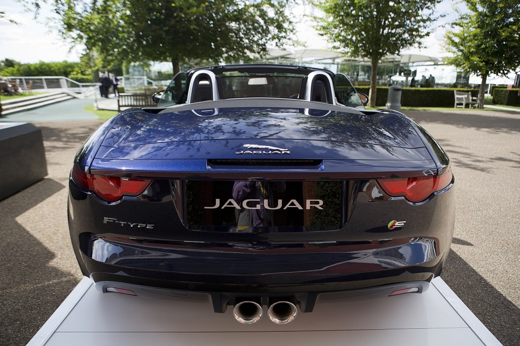 The rear view of a dark-blue 2014 Jaguar F-Type V8 S Convertible on a plinth at Goodwood
