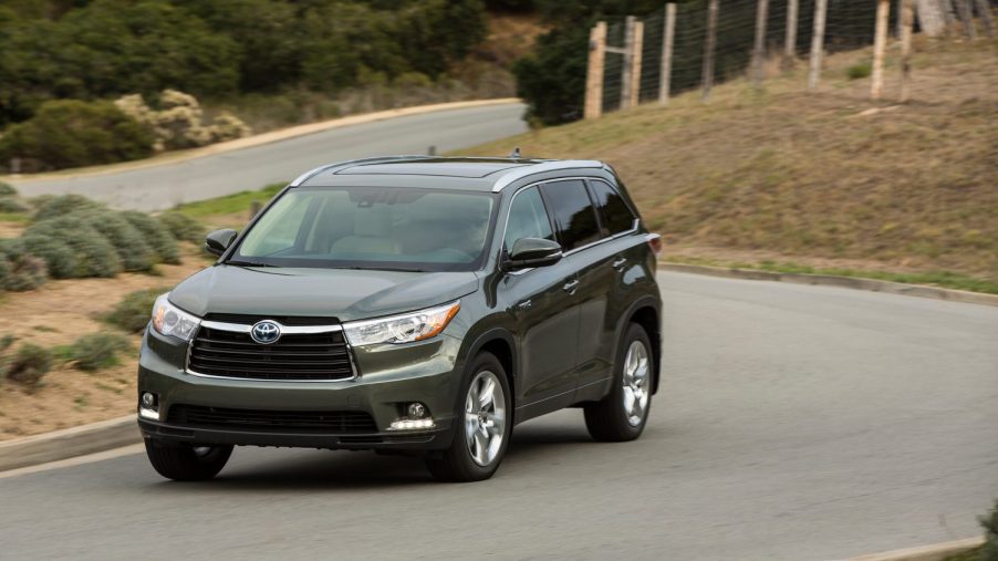 A gray 2014 Toyota Highlander driving down a winding road.