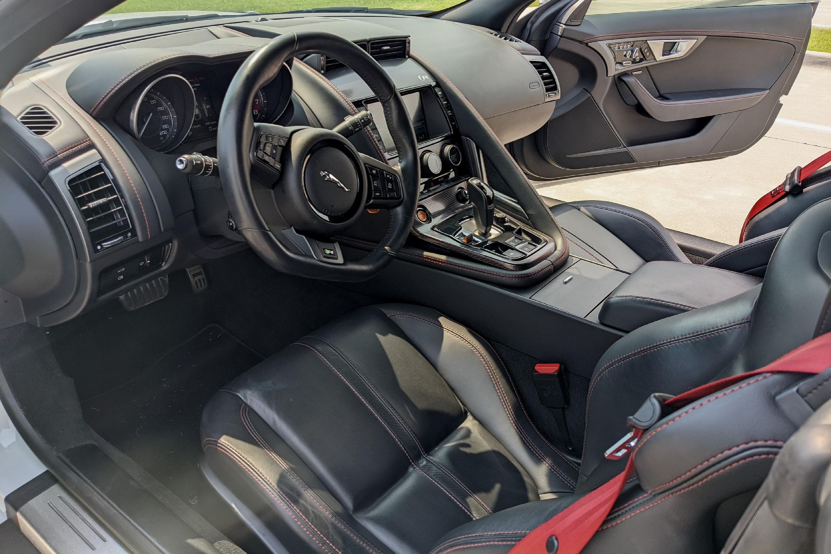 The red-stitched-black-leather sports seats and black-leather dashboard of a 2015 Jaguar F-Type Coupe with the Extended Leather Package