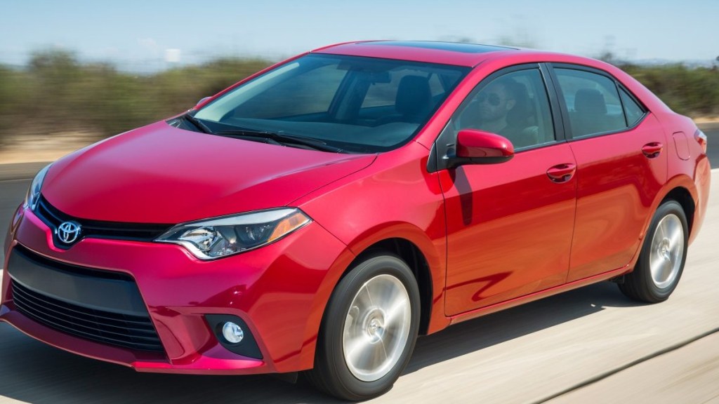 a red toyota corolla le driving along a road, showing off the modern styling this compact sedan offers