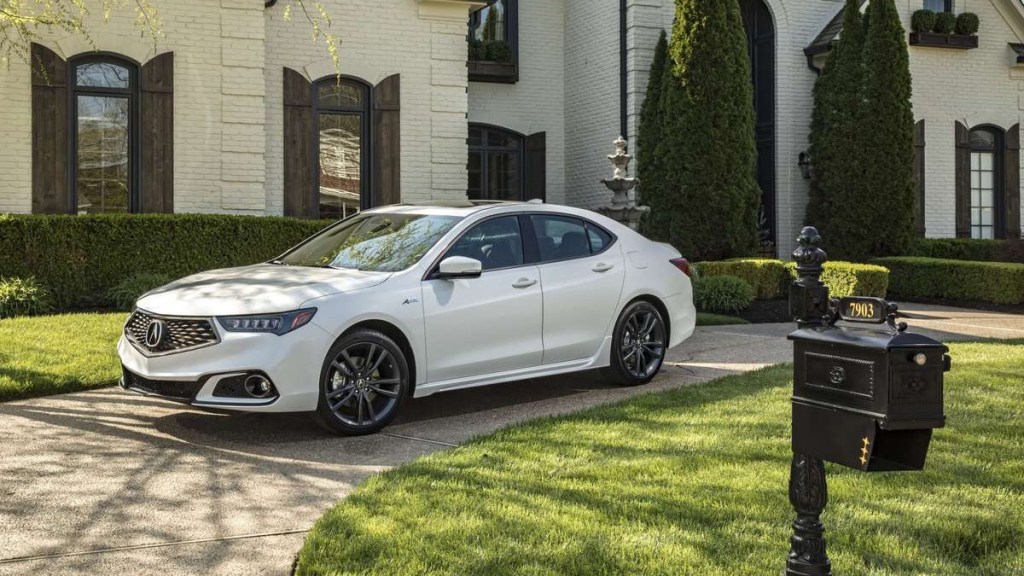 a white 2018 acura tlx, which is a great used sedan, is parked in front of a large white house