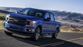 A blue 2018 Ford F-150 with mountains in the background.
