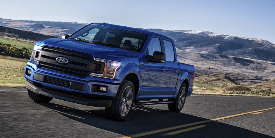 A blue 2018 Ford F-150 full-size truck with mountains in the background.