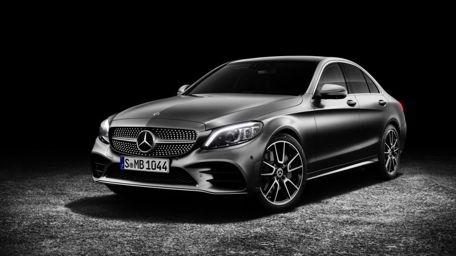 a black 2019 mercedes-benz c-class sedan is parked against a dark background showing off the sleek body lines and led lighting