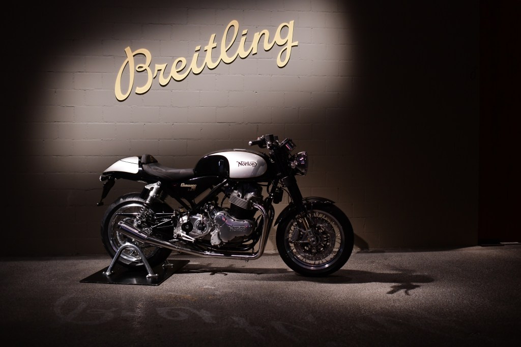 Side view of a 2019 Norton Commando 961 in black and white in front of a Breitling wall sign