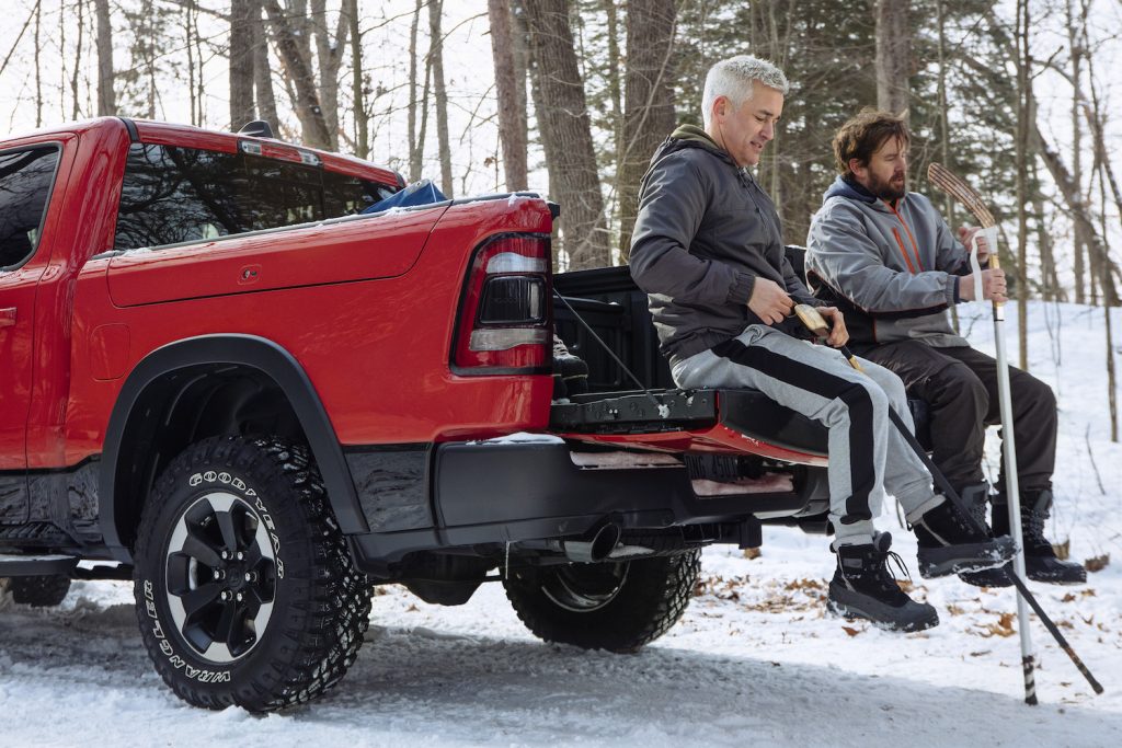 Two men sitting on the aluminum tailgate of a Ram 1500 pickup truck.
