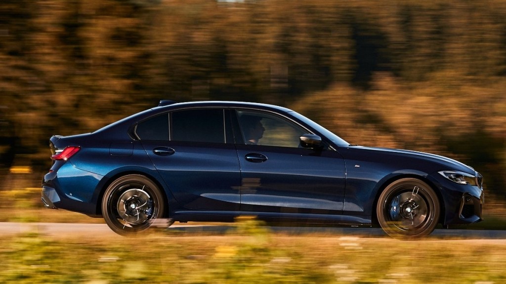 a dark blue 2020 bmw 3 series sedan flexes its performance chops while driving at sunset
