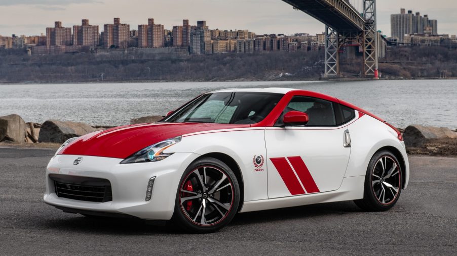 A red-and-white-decaled 2020 Nissan 370Z Heritage Edition in front of a city by a body of water