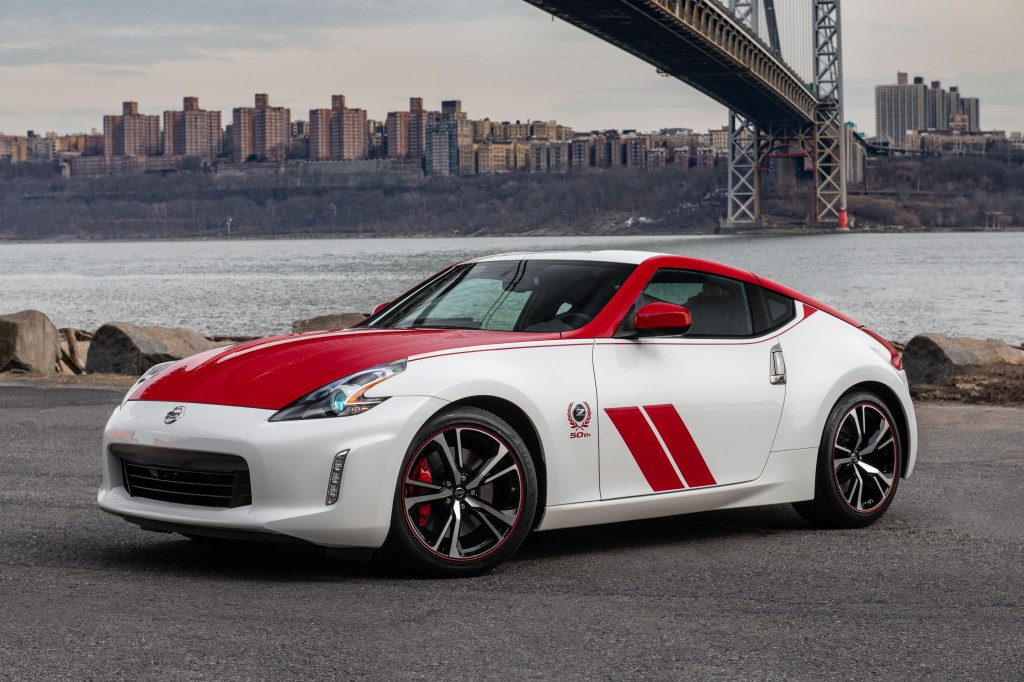 A red-and-white-decaled 2020 Nissan 370Z Heritage Edition in front of a city by a body of water