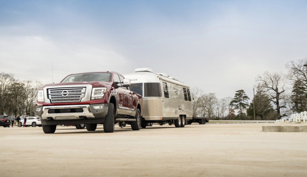 Red Nissan Titan XD pickup truck towing an Airstream travel camper.