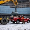 Construction workers setting a heavy piece of equipment in the bed of a half-ton Ford pickup truck.