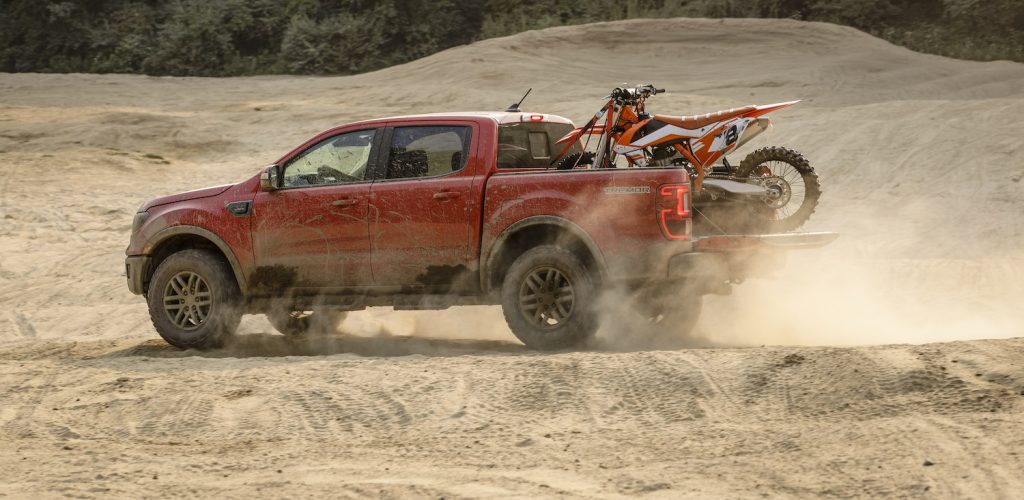 Publicity image of the 2021 Ford Ranger Tremor driving through the desert, a dirt bike in its bed.