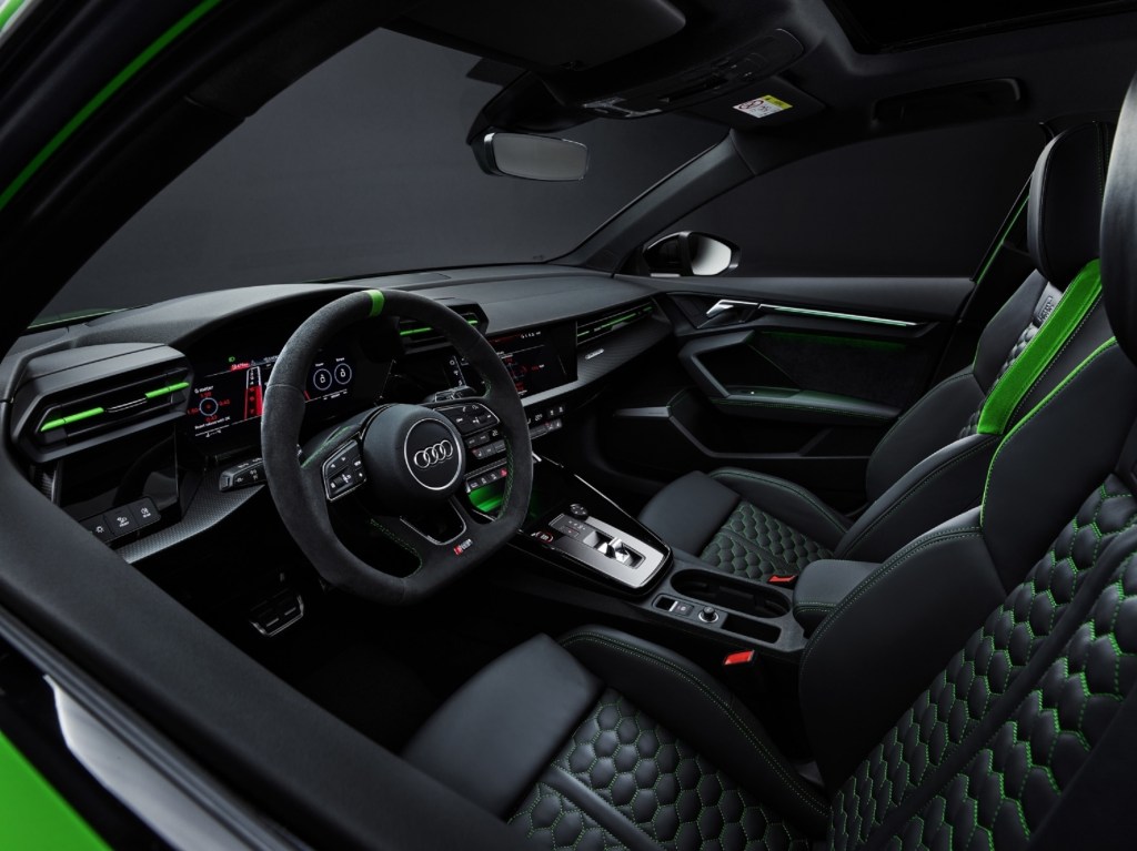 The black-quilted-leather front sports seats and dashboard, both with green accents, of a green 2022 Audi RS3