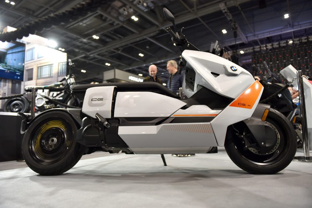 The side view of a white and orange 2022 BMW CE 04 electric motorcycle/scooter at the 2022 Carole Nash Motorcycle Show