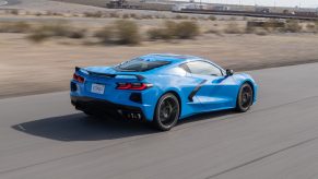 The rear 3/4 view of a blue 2022 Chevrolet C8 Corvette Stingray speeding down a desert track