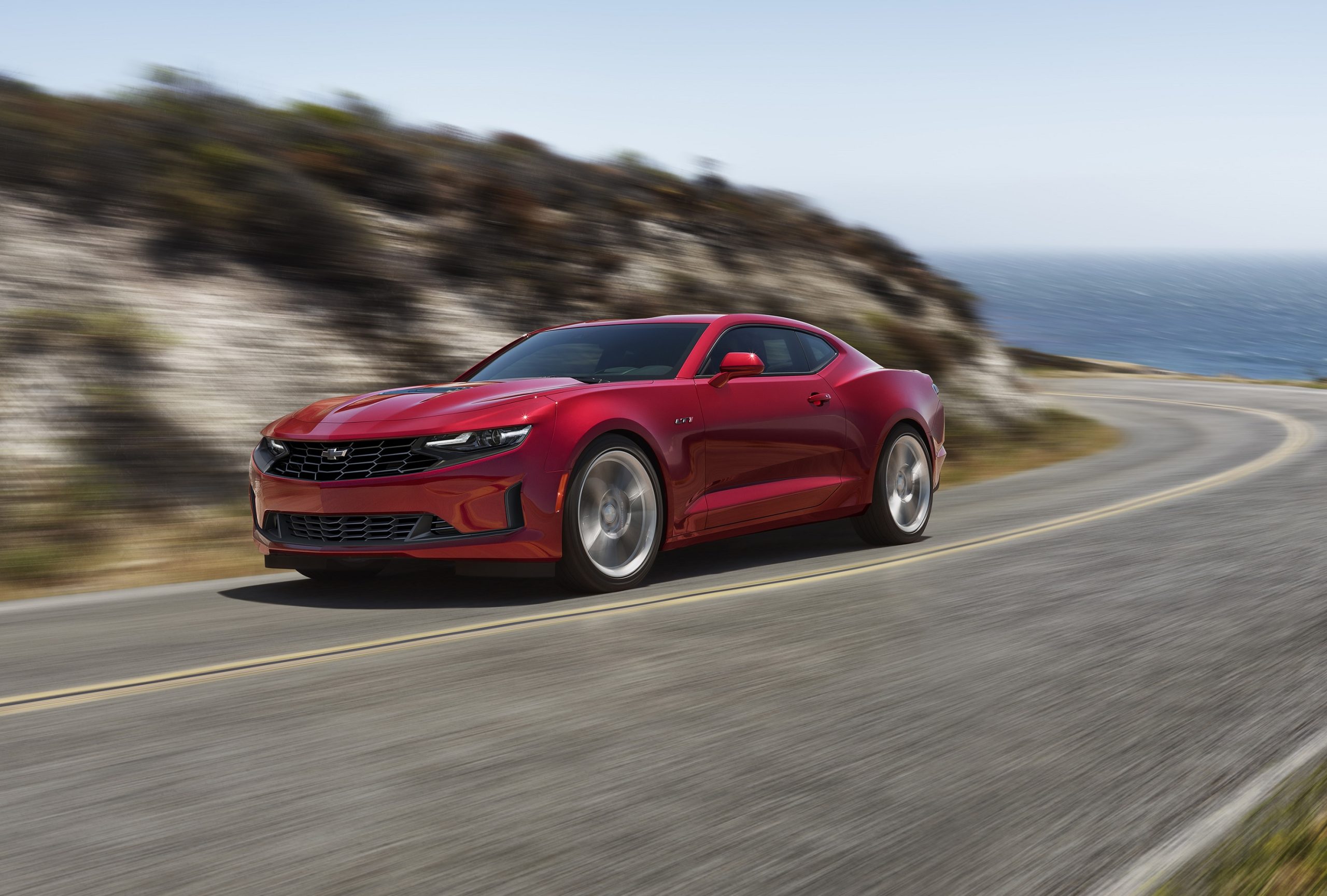 A red 2022 Chevrolet Camaro LT1 driving around an ocean road