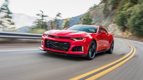 A red 2022 Chevrolet Camaro ZL1 driving around a mountain forest road