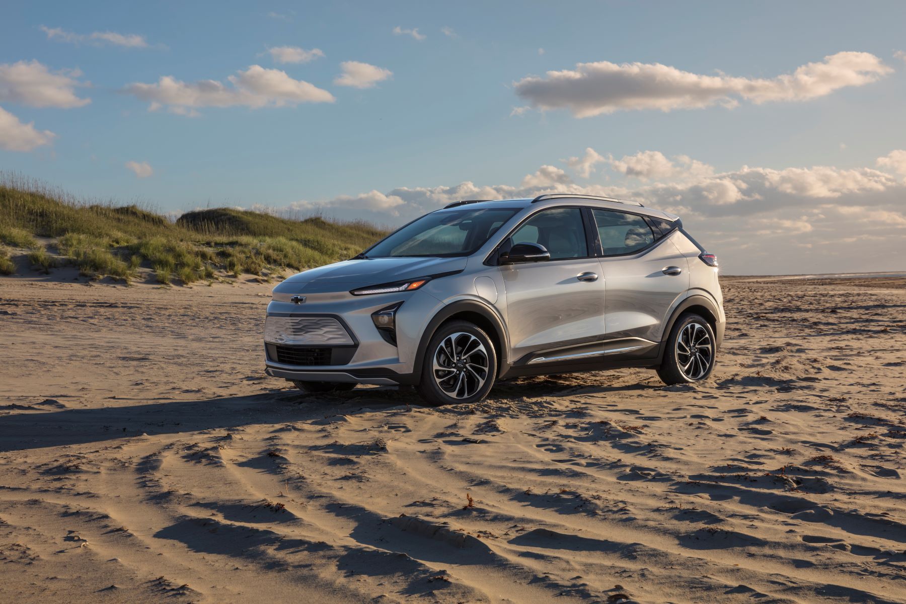 A silver gray 2022 Chevy Bolt EUV electric vehicle (EV) compact SUV parked on a sandy beach