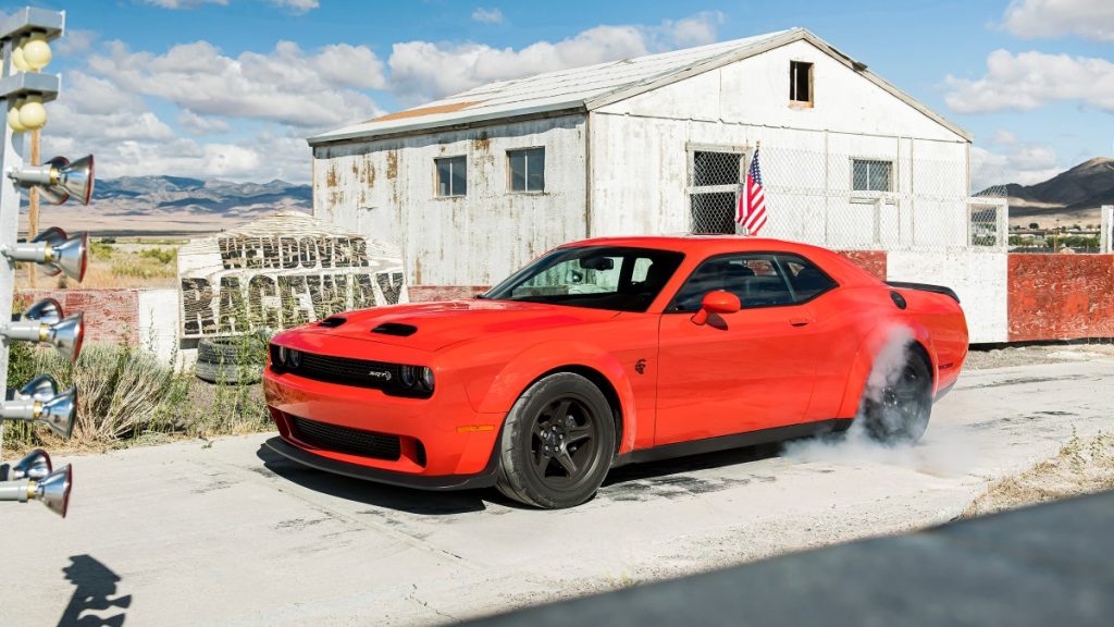 a 2022 red dodge challenger shows off its incredible supercharged power during a burnout