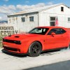 a red 2022 dodge challenger shows off its supercharged power with an aggressive burnout