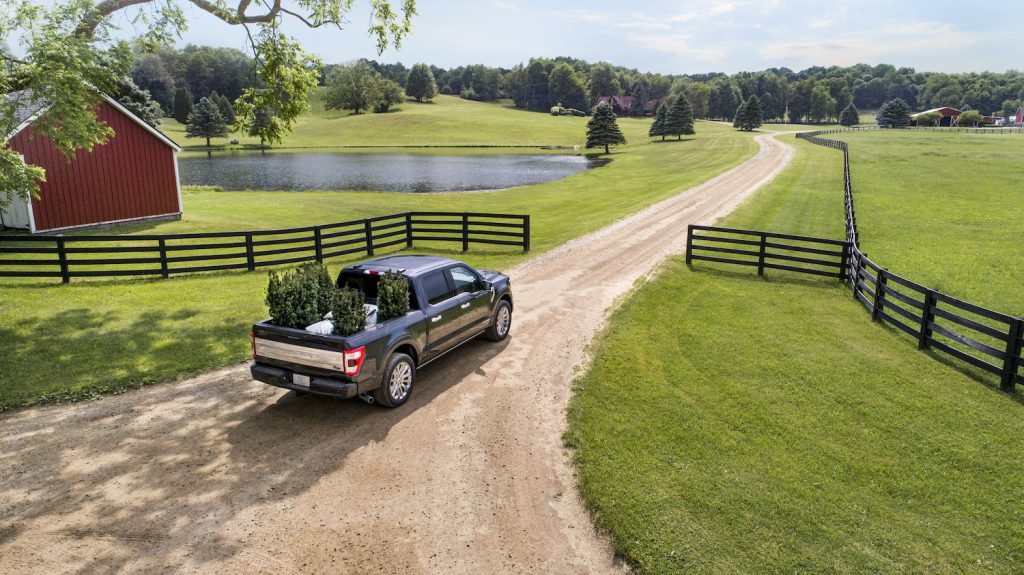 Ford F-150 half-ton pickup truck driving past a split-rail fence and into a barnyard.